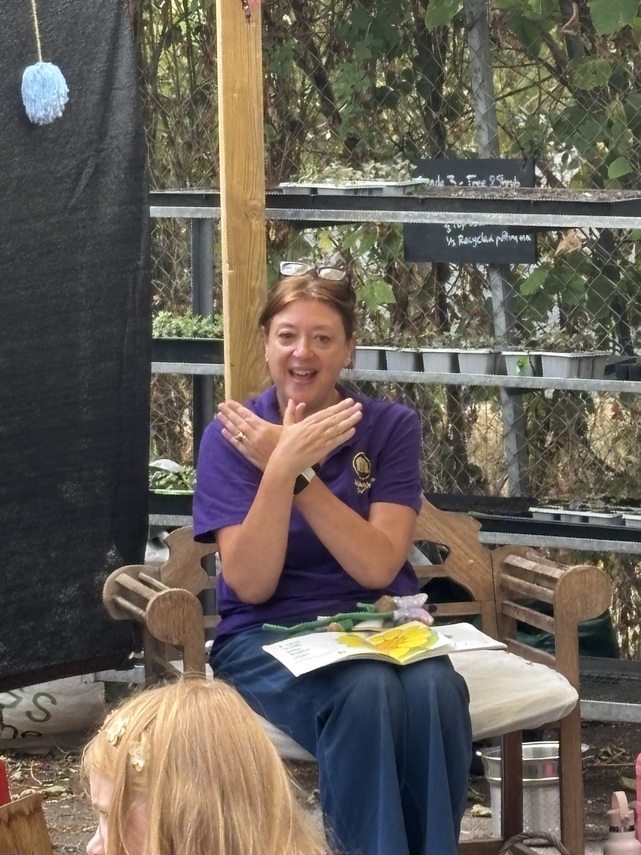 Woman in a purple Makaton Tutor Top signs butterfly 